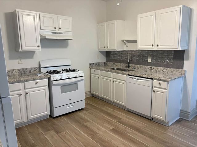 White kitchen with a gas range, dishwasher and granite countertops